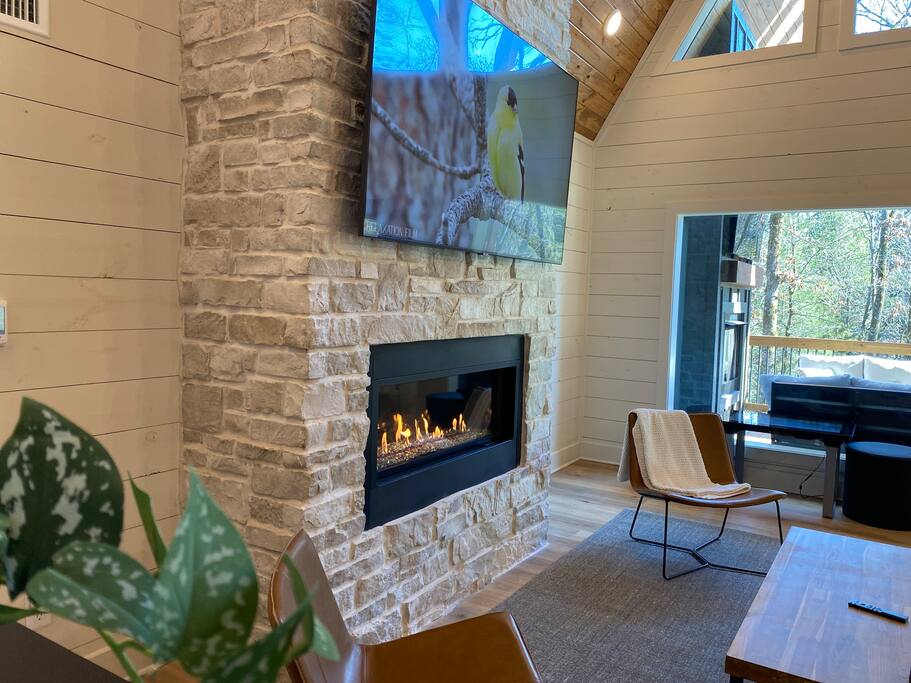 Relax on a cozy outdoor deck with a fireplace, plush seating, and nature views!