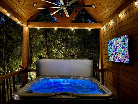 Relaxing outdoor hot tub with ambient lighting and vibrant TV display.
