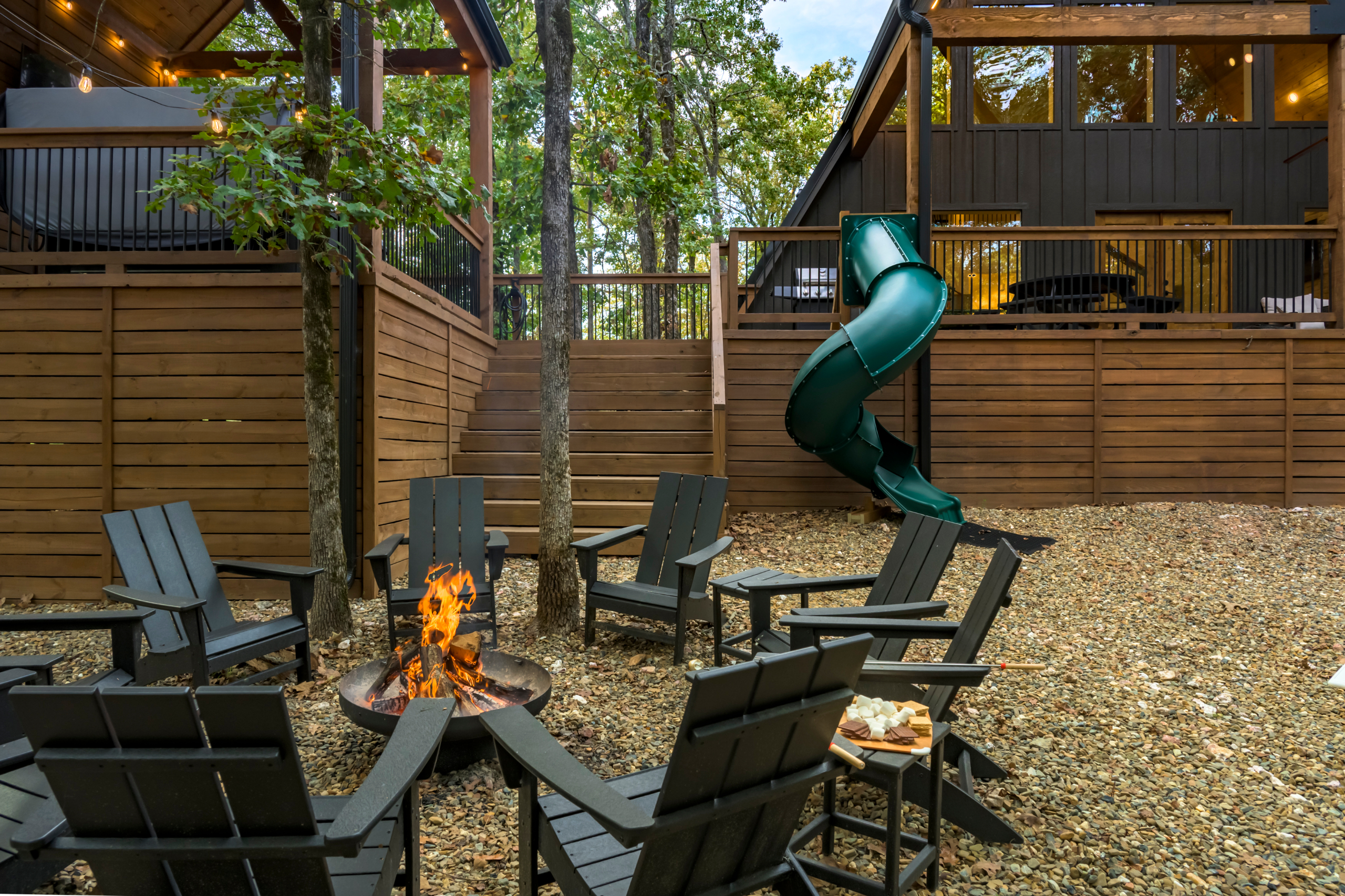 Back side of the cabin with firepit, chairs, smores and spiral slide off the back patio deck.