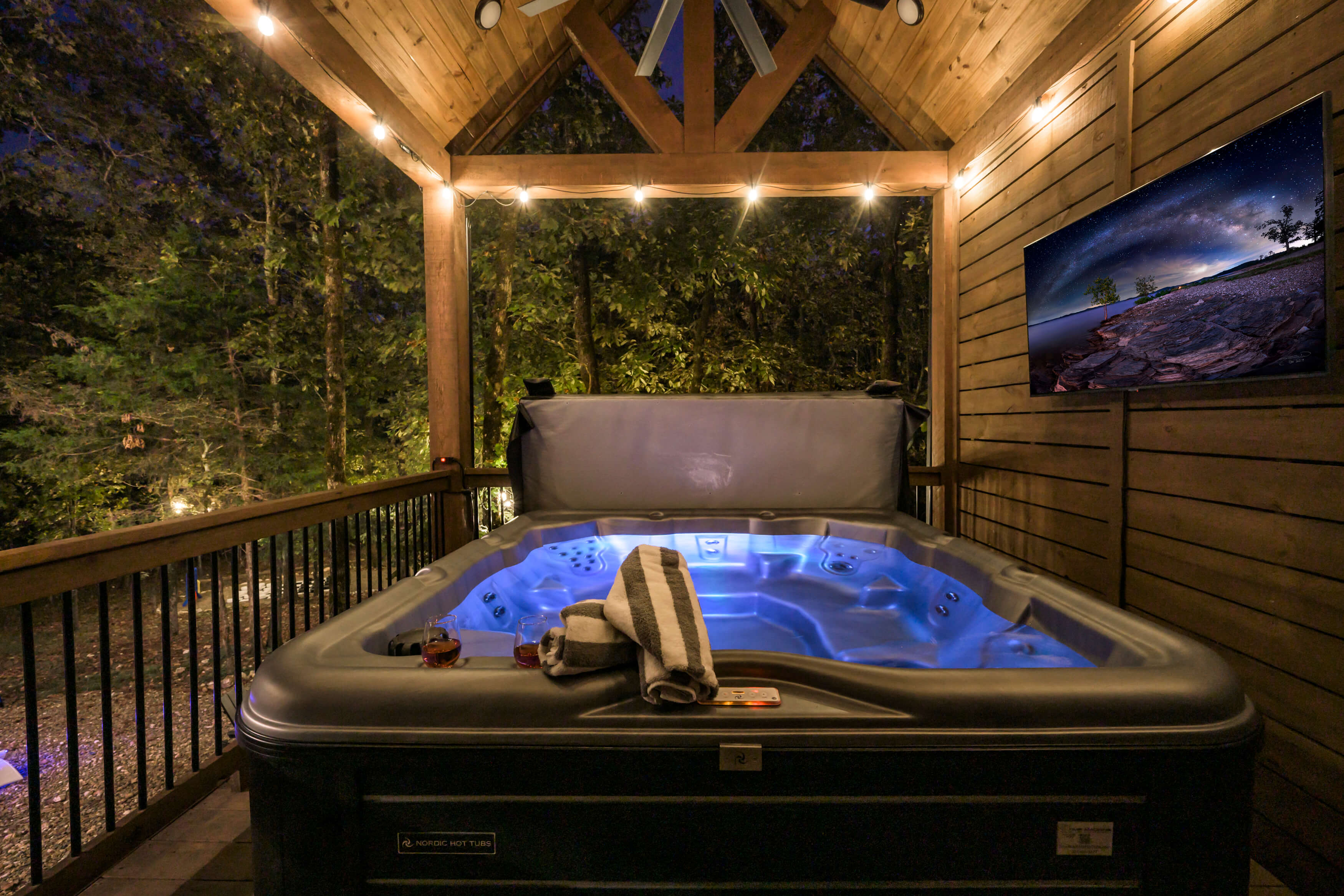 Relaxing outdoor hot tub with ambient lighting and vibrant TV display.