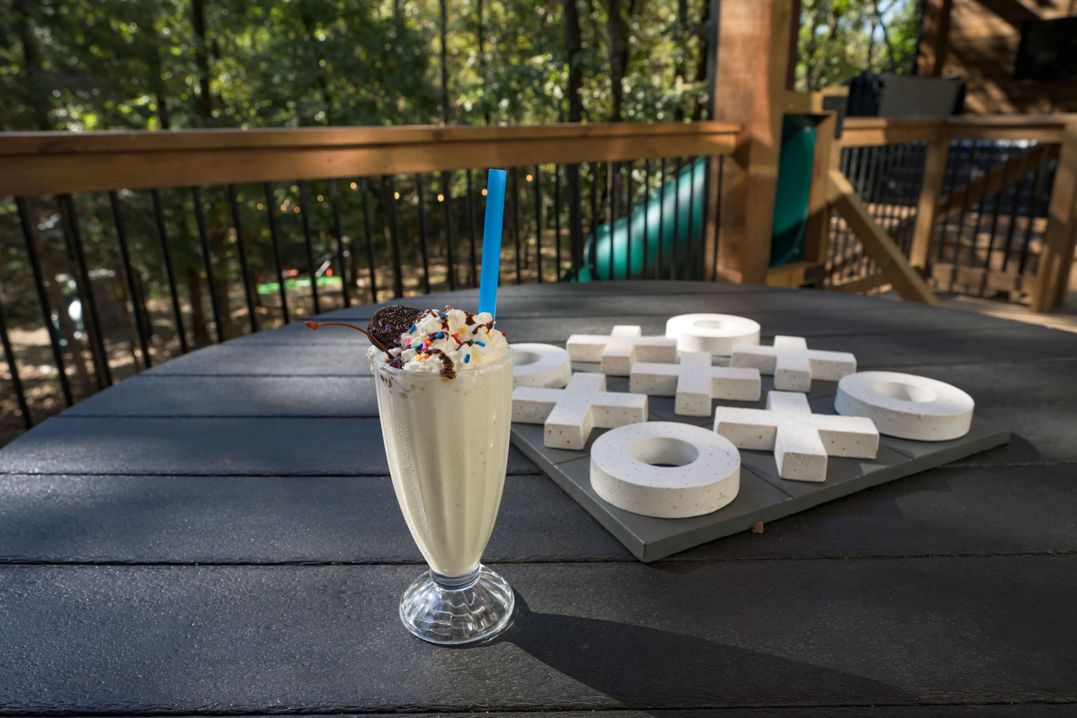 Vanilla milkshake and tic-tac-toe on a patio with scenic outdoor vibes.