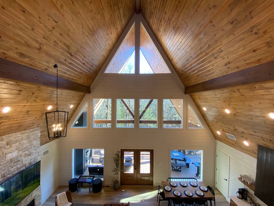 Cozy cabin living room with high ceilings, warm wood accents, and a fireplace!