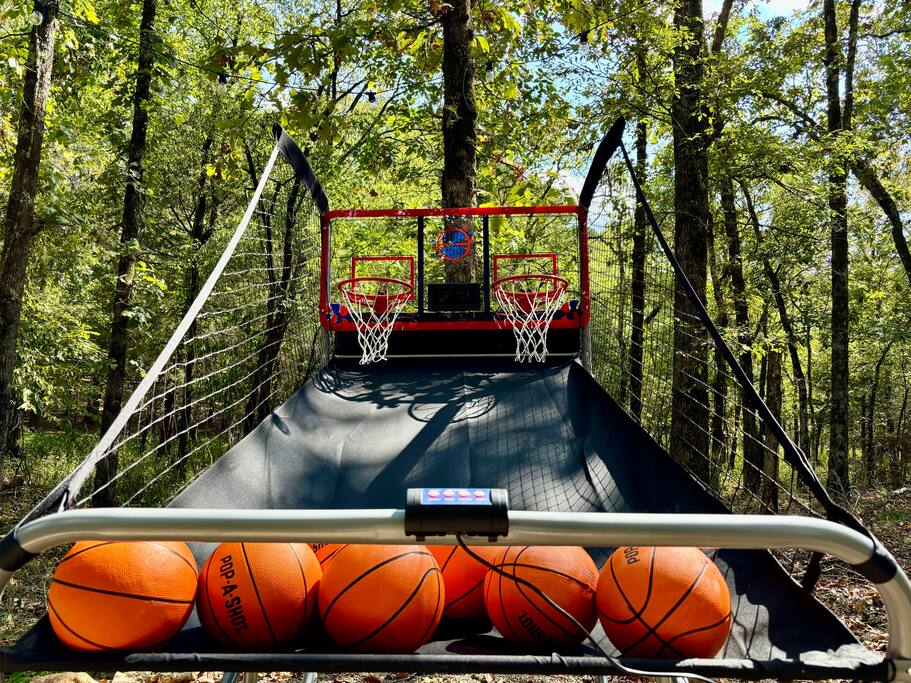 Outdoor basketball arcade fun amidst the peaceful charm of a forest retreat.