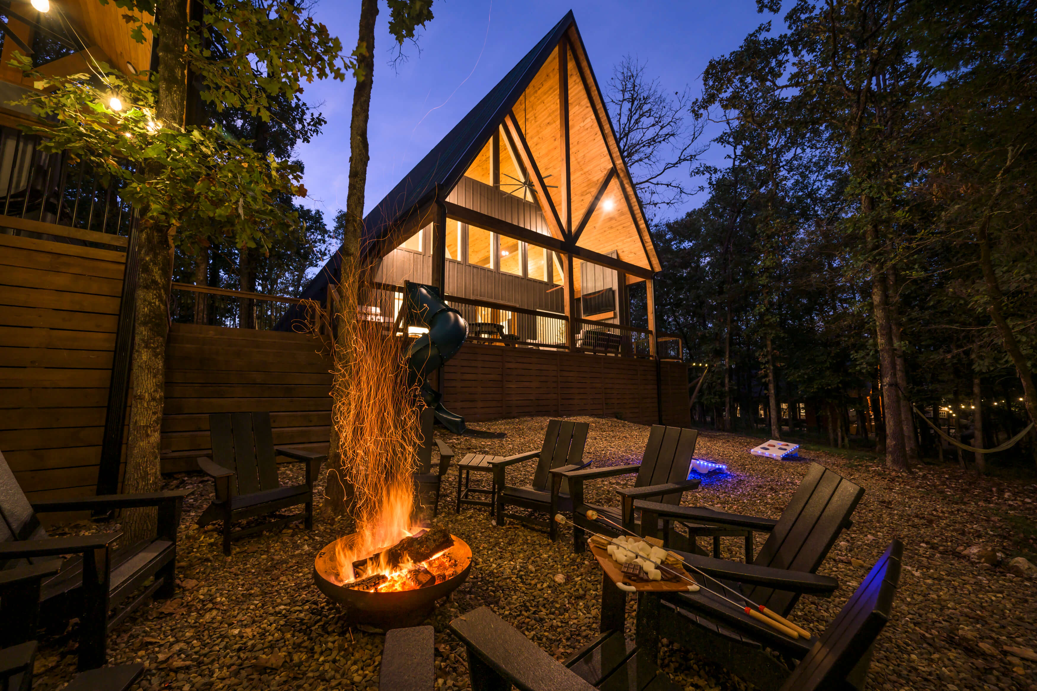 Warmly lit Yay frame cabin surrounded by tranquil forest at dusk in Broken Bow / Hochatown, OK.