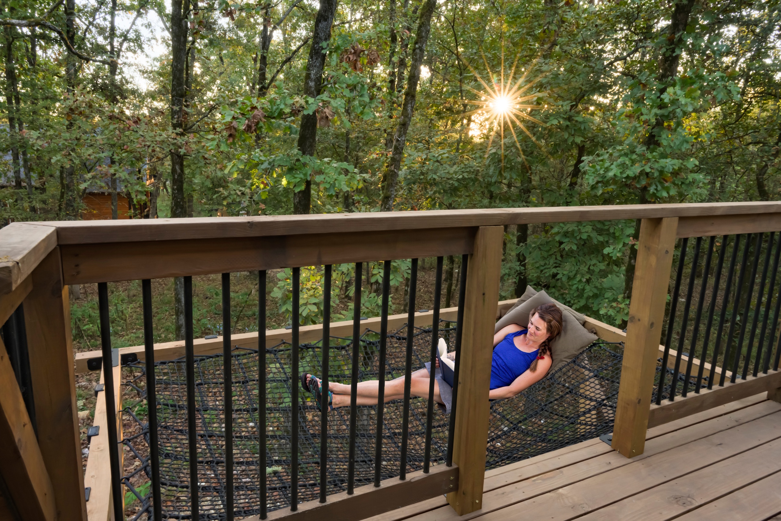 Guest laying on a large floating hammock with the lush green forest in the background.