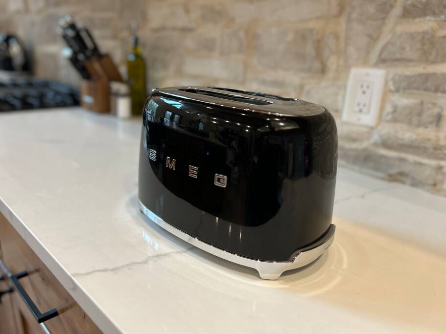 Sleek black SMEG toaster adds retro charm to a modern kitchen countertop.