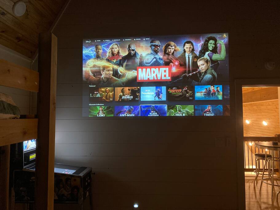 Homey cabin vibes with Marvel movies on the big screen—perfect night in!