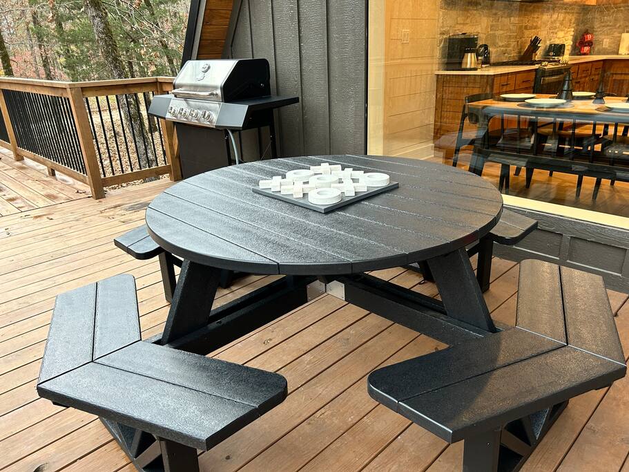 Cozy outdoor dining area with grill and tic-tac-toe game on table.