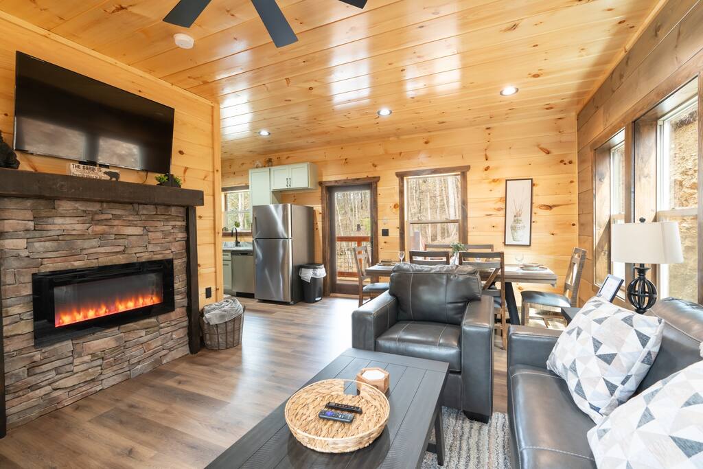The cabin's family room is a welcoming sanctuary, adorned with plush sofas and a  fireplace. Cozy throws invite relaxation while large windows frame breathtaking views. A haven for laughter and cherished family moments amidst the serene wilderness
