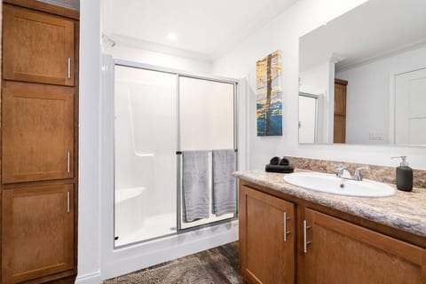 Spacious ensuite master bathroom with walk-in shower, soft performance bath and hand towels, and storage space.