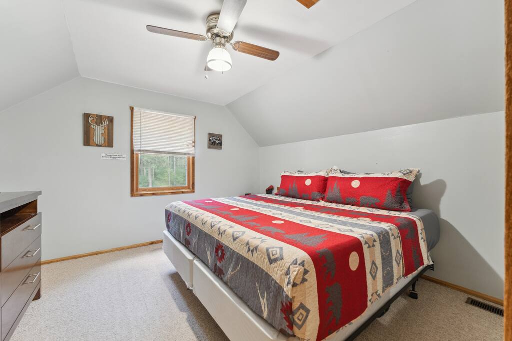 Upstairs cabin king bedroom with Roku TV, dresser, alarm clock with USB charger, ceiling fan, portable fan, extra pillow and blankets, and closet with hangers Upstairs cabin king bedroom with Roku TV, dresser, alarm clock with USB charger, ceiling fan, portable fan, extra pillow and blankets, and closet with hangers - Eagle Bluff Estate - Mauston