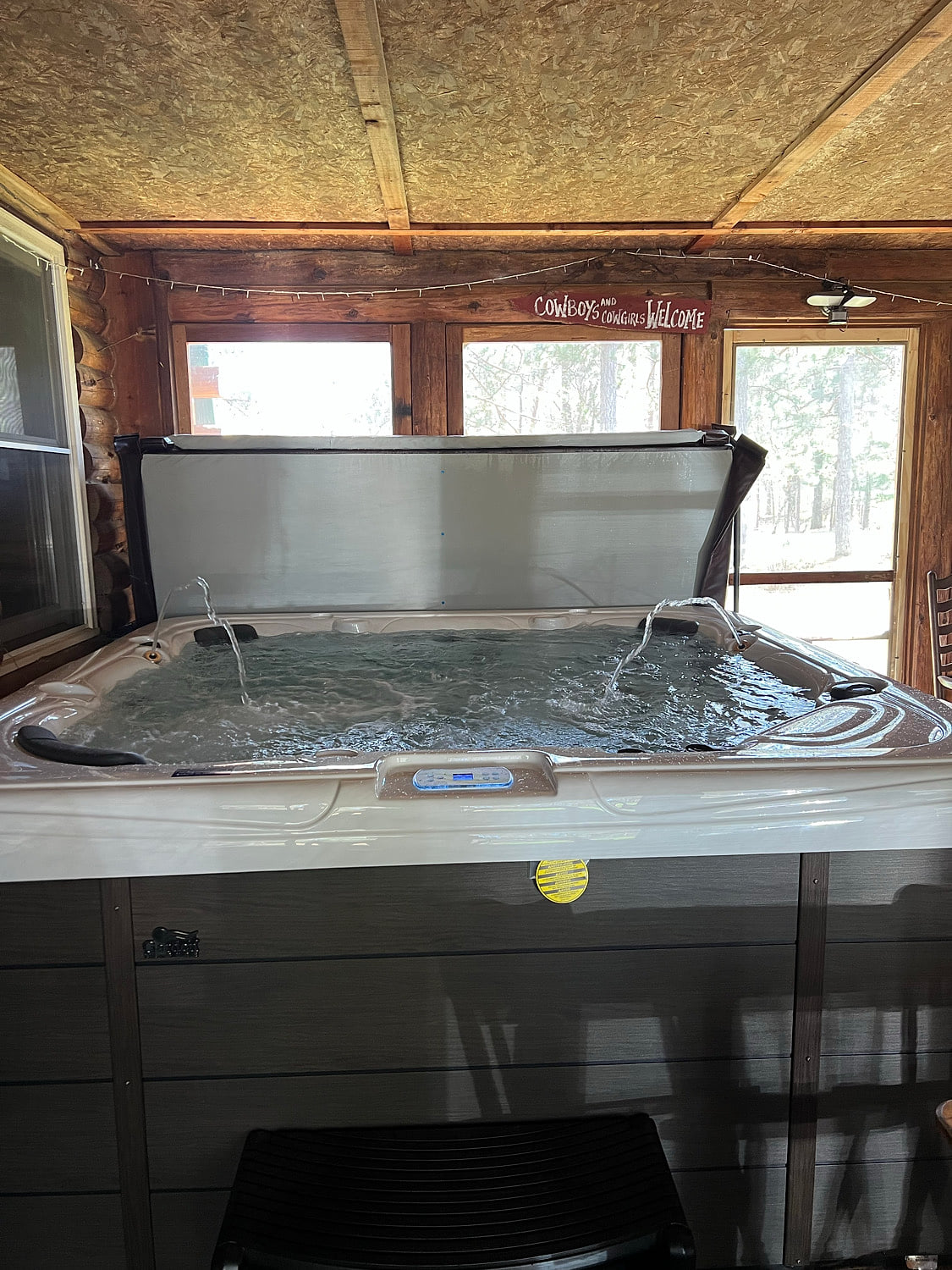 Covered hot tub on rustic screened porch—soak with woodland views