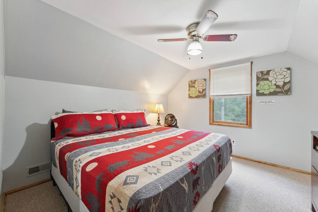 Upstairs cabin king bedroom with Roku TV, dresser, alarm clock with USB charger, ceiling fan, portable fan, extra pillow and blankets, and closet with hangers Upstairs cabin king bedroom with Roku TV, dresser, alarm clock with USB charger, ceiling fan, portable fan, extra pillow and blankets, and closet with hangers - Eagle Bluff Estate - Mauston