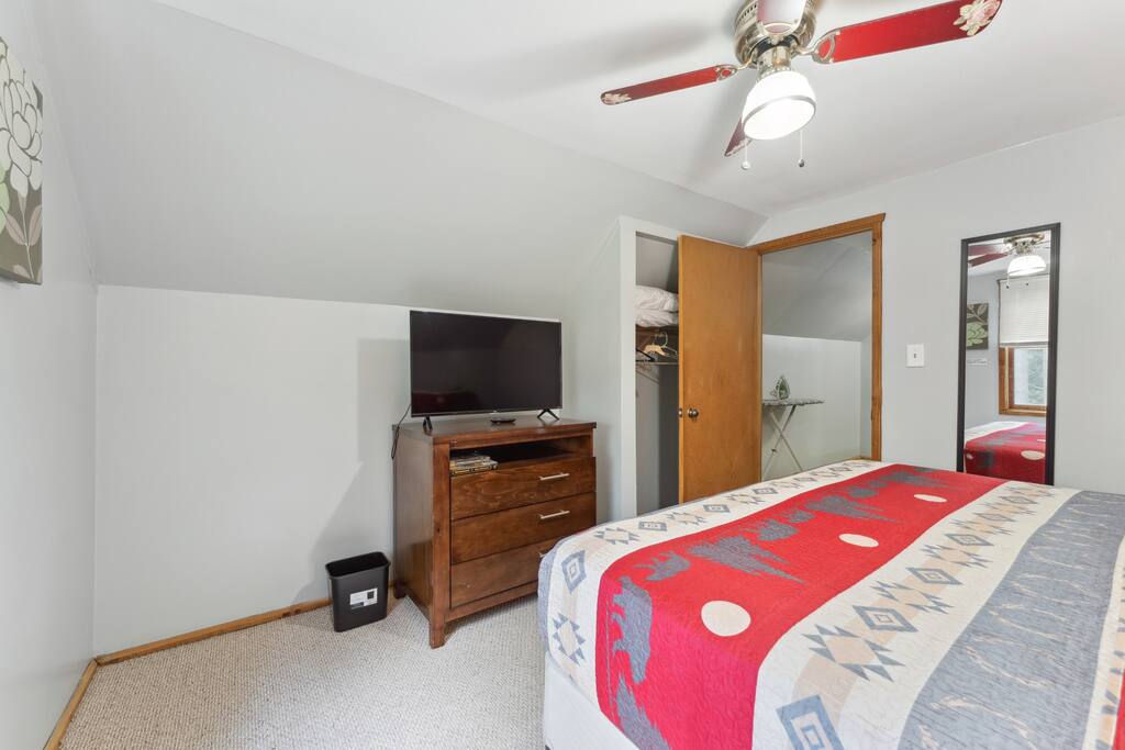 Upstairs cabin king bedroom with Roku TV, dresser, alarm clock with USB charger, ceiling fan, portable fan, extra pillow and blankets, and closet with hangers Upstairs cabin king bedroom with Roku TV, dresser, alarm clock with USB charger, ceiling fan, portable fan, extra pillow and blankets, and closet with hangers - Eagle Bluff Estate - Mauston