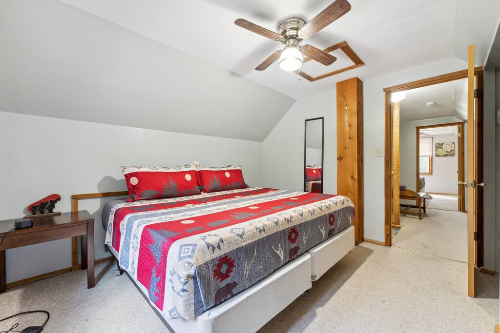 Upstairs cabin king bedroom with Roku TV, dresser, alarm clock with USB charger, ceiling fan, portable fan, extra pillow and blankets, and closet with hangers Upstairs cabin king bedroom with Roku TV, dresser, alarm clock with USB charger, ceiling fan, portable fan, extra pillow and blankets, and closet with hangers - Eagle Bluff Estate - Mauston