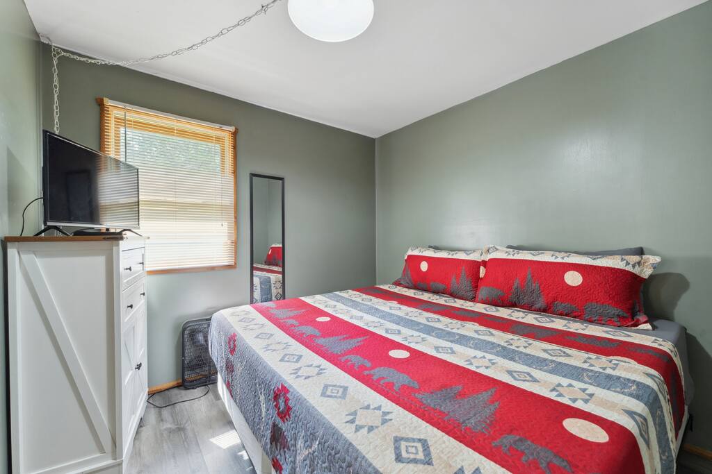 Main-level cabin king bedroom with Roku TV, dresser, alarm clock with USB charger, portable fan, and closet with hangers Main-level cabin king bedroom with Roku TV, dresser, alarm clock with USB charger, portable fan, and closet with hangers - Eagle Bluff Estate - Mauston