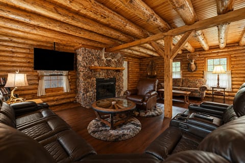 Rustic log cabin lounge with stone fireplace and cozy leather seating