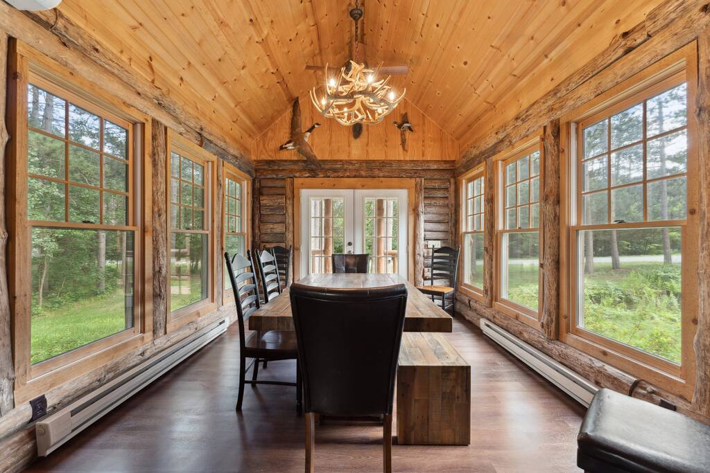 The four-seasons dining room has great taste of cabin decor, featuring a beautiful table with 8 chairs and a bench with more seating in the kitchen. The four-seasons dining room has great taste of cabin decor, featuring a beautiful table with 8 chairs and a bench with more seating in the kitchen. - Eagle Bluff Estate - Mauston