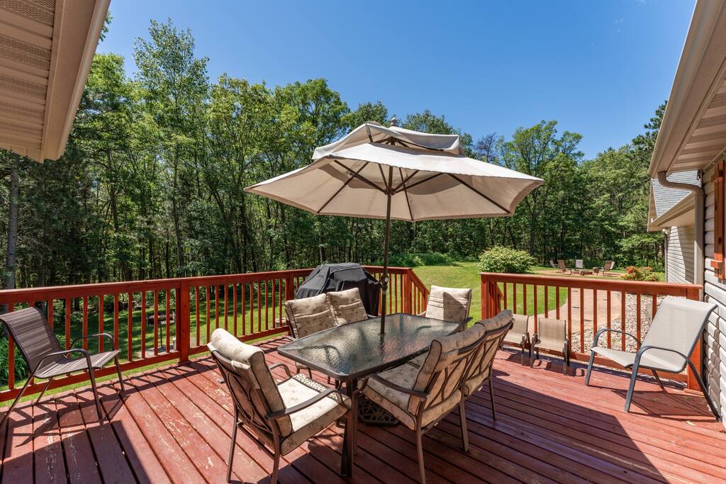 Back deck featuring a table with umbrella and 8 chairs, additional 2 kids chairs plus gas and charcoal grills. It has a great view of the forest-lined backyard Back deck featuring a table with umbrella and 8 chairs, additional 2 kids chairs plus gas and charcoal grills. It has a great view of the forest-lined backyard - Bear Cove Escape - Lyndon Station