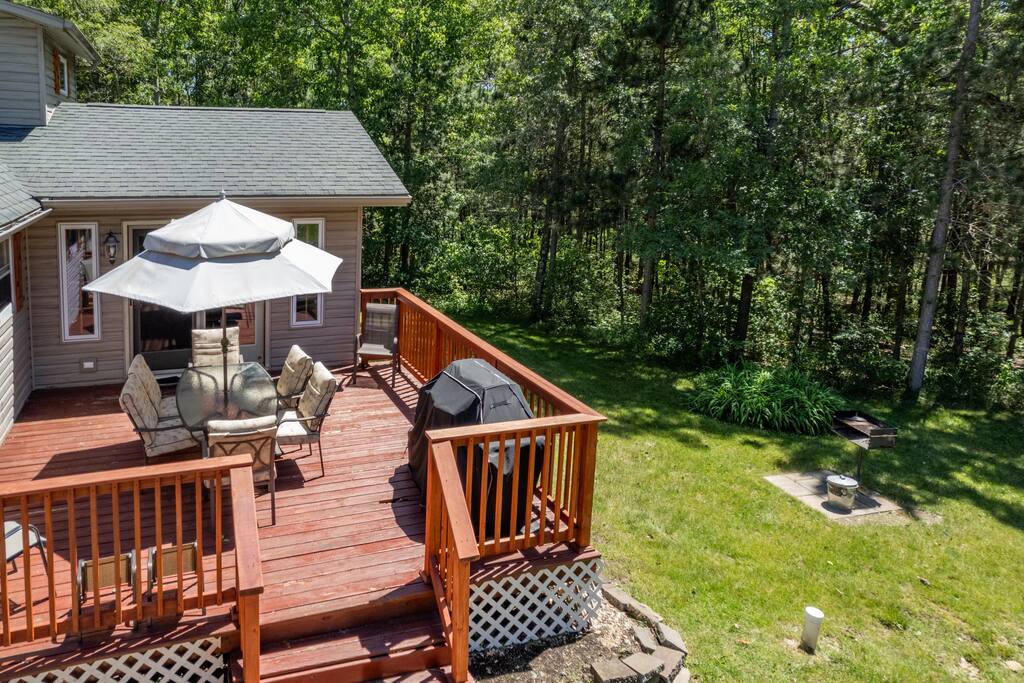 Back deck featuring a table with umbrella and 8 chairs, additional 2 kids chairs plus gas and charcoal grills. It has a great view of the forest-lined backyard Back deck featuring a table with umbrella and 8 chairs, additional 2 kids chairs plus gas and charcoal grills. It has a great view of the forest-lined backyard - Bear Cove Escape - Lyndon Station