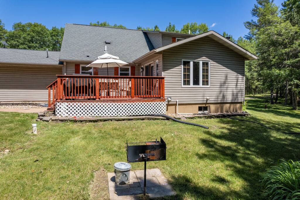 Back deck featuring a table with umbrella and 8 chairs, additional 2 kids chairs plus gas and charcoal grills. It has a great view of the forest-lined backyard Back deck featuring a table with umbrella and 8 chairs, additional 2 kids chairs plus gas and charcoal grills. It has a great view of the forest-lined backyard - Bear Cove Escape - Lyndon Station