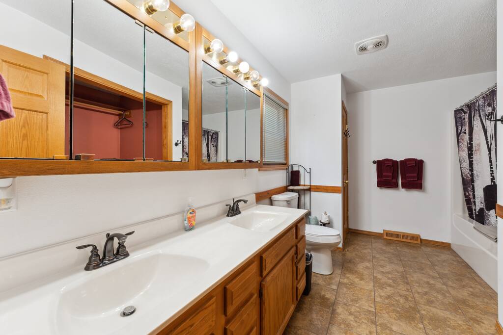 Full bathroom with jetted bathtub, toilet, two sinks and vanity, shower gel, conditioner, shampoo, iron & ironing board, and towels supplied. Full bathroom with jetted bathtub, toilet, two sinks and vanity, shower gel, conditioner, shampoo, iron & ironing board, and towels supplied. - Bear Cove Escape - Lyndon Station