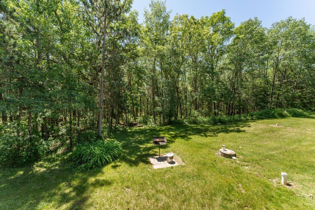 Back deck featuring a table with umbrella and 8 chairs, additional 2 kids chairs plus gas and charcoal grills. It has a great view of the forest-lined backyard Back deck featuring a table with umbrella and 8 chairs, additional 2 kids chairs plus gas and charcoal grills. It has a great view of the forest-lined backyard - Bear Cove Escape - Lyndon Station