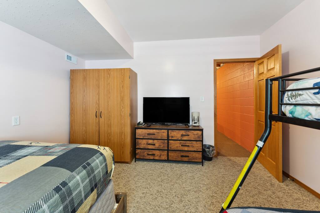 Basement bedroom with one queen bed, one bunk bed with full bed on the bottom and twin on top, dresser, Roku TV, USB charging ports, alarm clock, hangers and closet Basement bedroom with one queen bed, one bunk bed with full bed on the bottom and twin on top, dresser, Roku TV, USB charging ports, alarm clock, hangers and closet - Bear Cove Escape - Lyndon Station