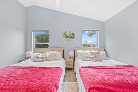 This bedroom offers two queen beds for ultimate relaxation, accompanied by a comforting ceiling fan and windows adorned with blinds.