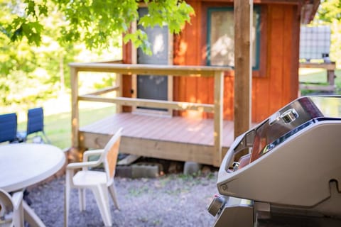 The grill in a small stone patio area with picnic table and chairs.