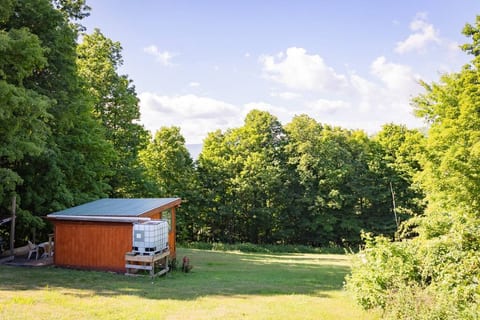 The view of cabin in the surrounding field.  Taken from the dirt road.  The water tank is where the rain is stored for the eco-bath tub.