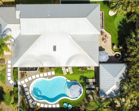 From above, you can see the thoughtfully designed outdoor retreat with a sparkling heated pool, fire pit for gathering, putting green, tropical landscaping, and multiple spaces for gathering and relaxing.