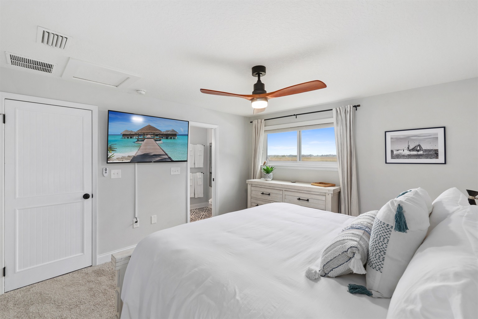 Primary bedroom with king bed, smart TV, and en suite bathroom - Marsh View: Renovated close to Mayo! Heated pool - Jacksonville Beach