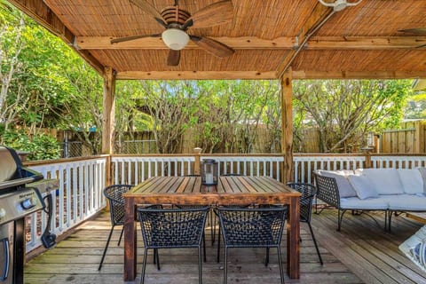 The beautiful covered patio area has a dining table, grill, hanging chair, and conversation area, perfect for enjoying your private backyard oasis