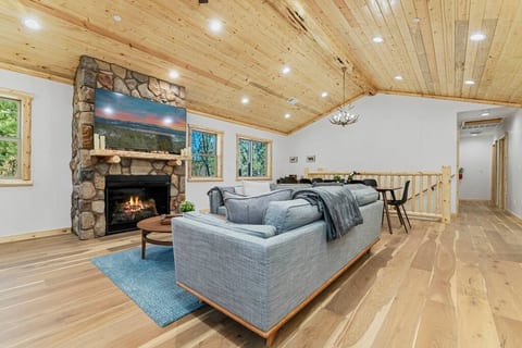 Open concept upstairs living area/dining area with enclosed gas fireplace and 65 inch TV