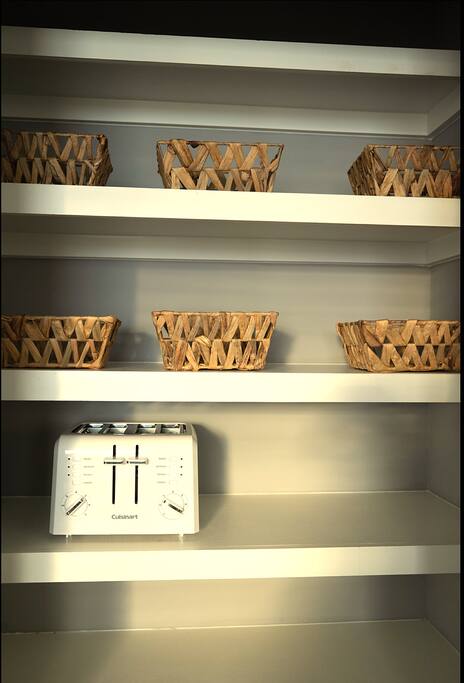 Pantry | Organized Storage | Kitchen Essentials
Neatly arranged pantry shelves with woven baskets for organized storage and a white 4-slice Cuisinart toaster—combining function and simplicity for your stay.