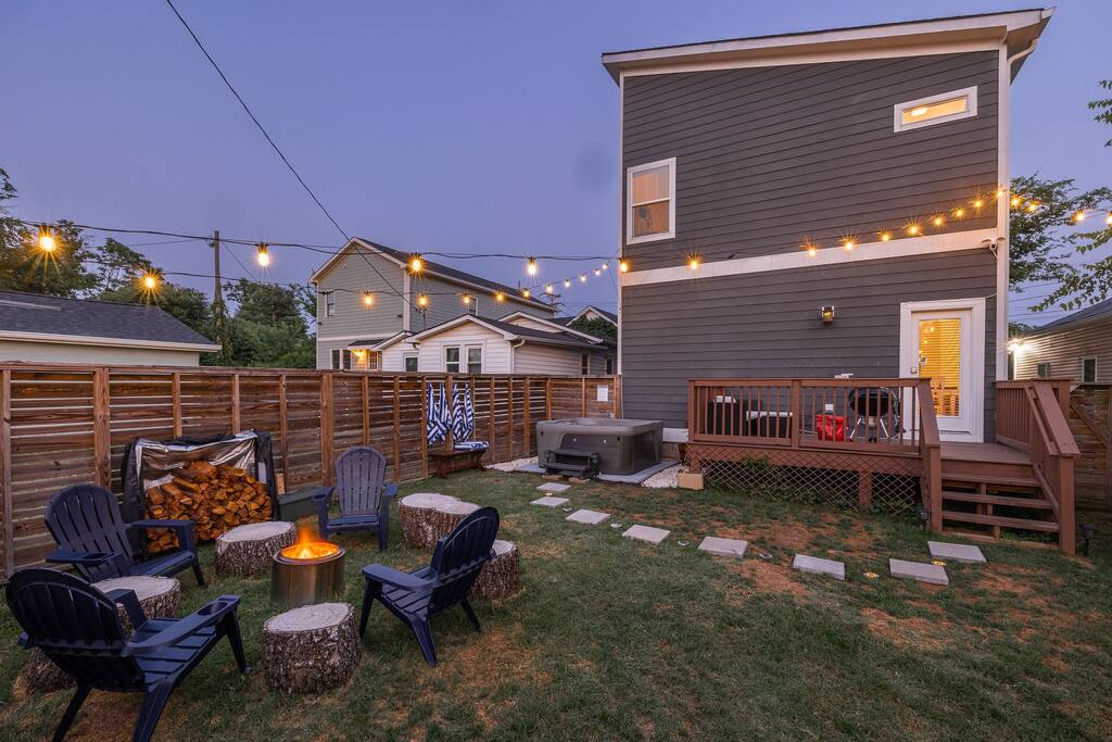 Golden hour view of the entire backyard. Bistro lights, fire pit, hot tub and BBQ