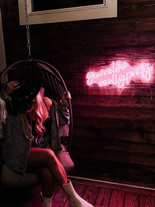 On the upstairs balcony, you'll find a 'You're like really pretty' neon sign wall next to a hanging egg chair for a perfect photo opportunity!