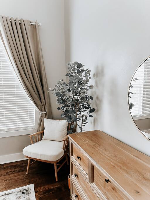 Bedroom Corner | Relaxing Nook | Natural Light
Peaceful corner with a cozy chair, floor plant, wood dresser, and round mirror—framed by soft curtains and natural light, perfect for quiet moments.