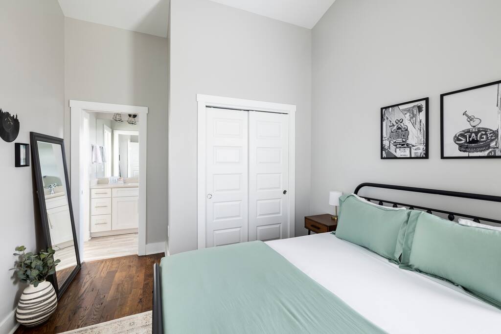 Bedroom | Queen Room | Closet & Decor
Bright bedroom with a queen bed, light green bedding, double-door closet, music-themed wall art, and full-length mirror—steps from an en-suite jack-and-jill bathroom.