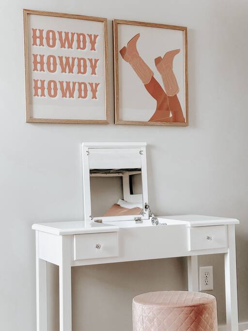 Bedroom | Vanity Area | Western Decor
Chic white vanity with a flip-top mirror and blush pink stool, set beneath playful Western-themed wall art—perfect for getting ready in style.