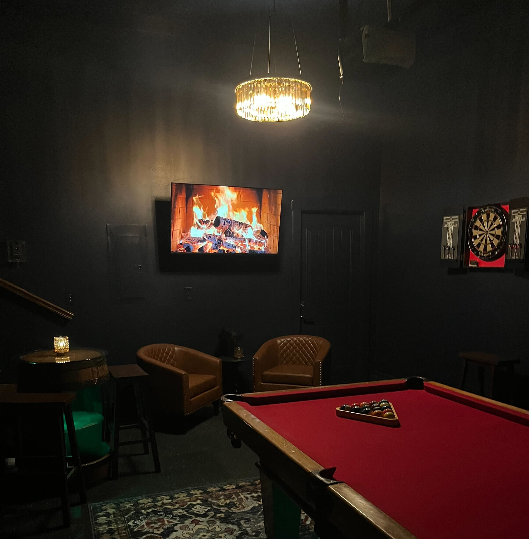 Moody game lounge with red felt pool, darts, TV and cozy seating