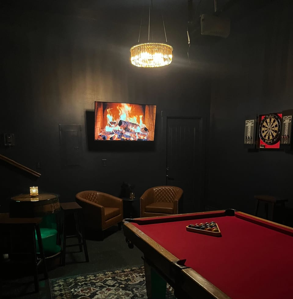Moody game lounge with red felt pool, darts, TV and cozy seating