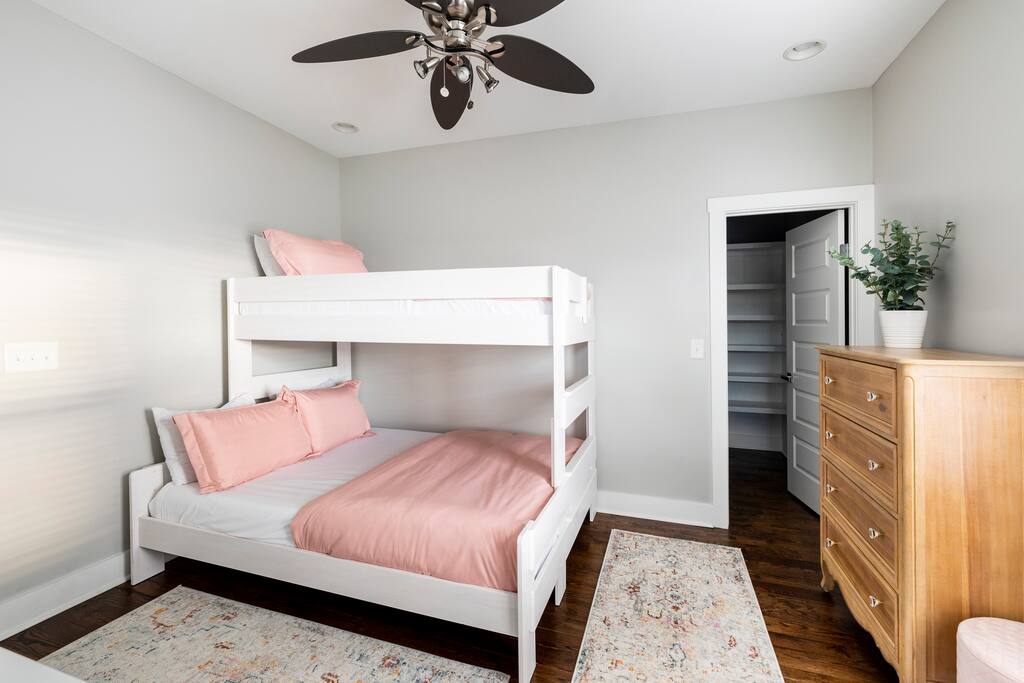 Bedroom | Bunk Room | Storage & Comfort
Spacious bedroom with a twin-over-queen bunk bed, soft pink bedding, ceiling fan, wooden dresser, and walk-in closet—perfect for groups or families needing comfort and extra storage.