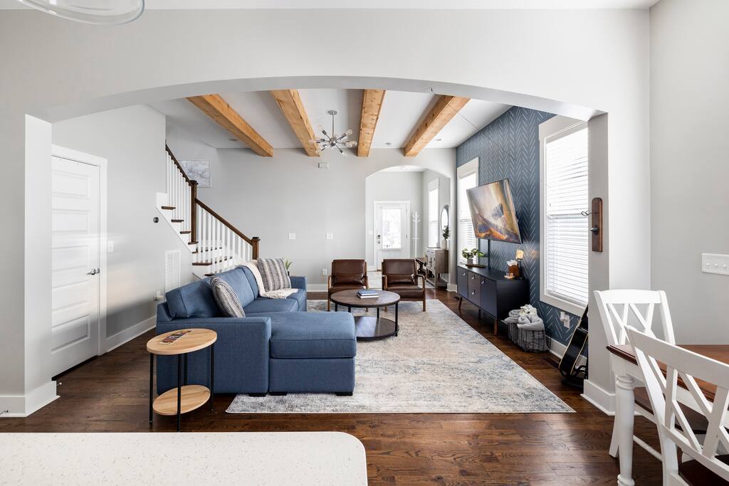 Living Room | Open Concept | 1st Floor
Bright and spacious living room with exposed wooden beams, a sectional sofa, leather chairs, accent wall with mounted TV, and rustic touches—perfect for relaxing and gathering with your group.