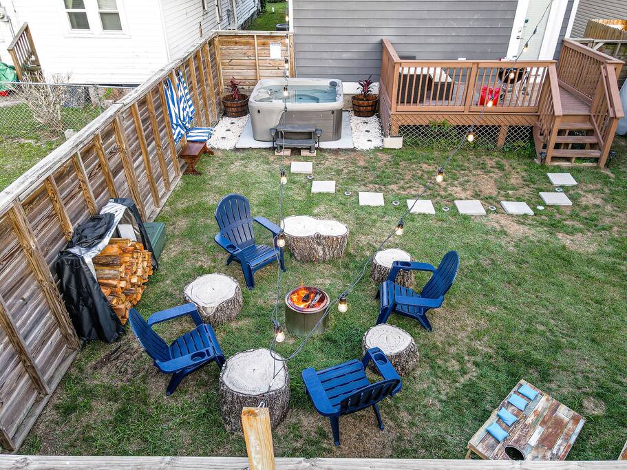 Aerial shot of the backyard with a fire pit with unlimited firewood, hot tub, corn hole, BBQ and more!