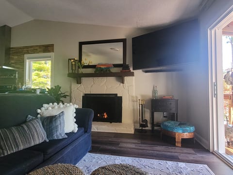 Living Room with sectional sofa, wood burning fireplace and a 65" smart TV
