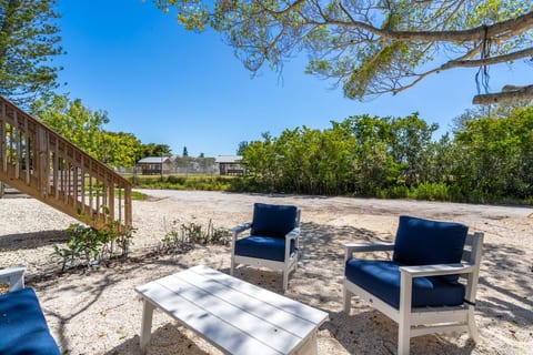 Back patio sitting area with comfortable plush sectional sofa and arm chairs facing park and small mangrove preserve.