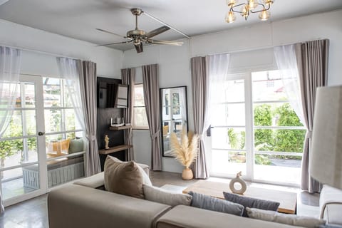 A cozy living room bathed in natural light, featuring sleek shelves, a modern TV for entertainment, and comfortable seating, all inviting relaxation.