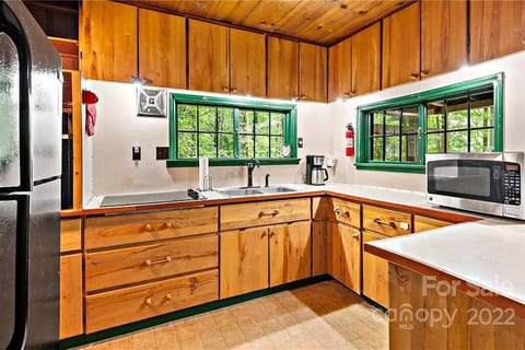 Full kitchen with cooktop, in-wall oven, fridge, and microwave. Wide windows look out into the wooded area and slide open easily to bring the fresh air in!